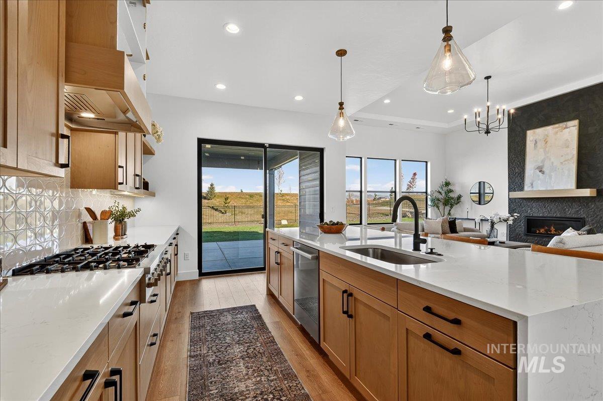 7714 West Flathead Lake Street, Unit ASPEN Eagle, ID 83616 - Photo 13 of 30 Kitchen featuring light stone counters, light wood-style floors, a fireplace, decorative light fixtures, and recessed lighting