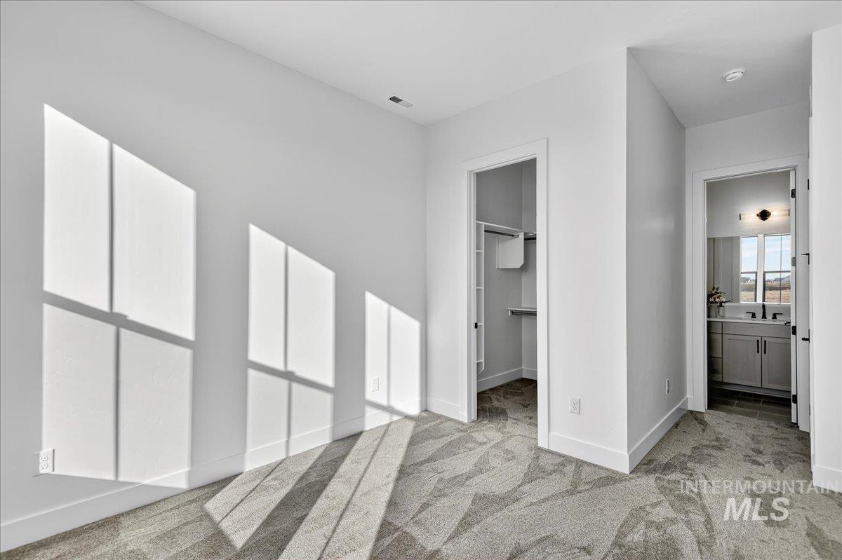 7714 West Flathead Lake Street, Unit ASPEN Eagle, ID 83616 - Photo 21 of 30 Unfurnished bedroom featuring a spacious closet, light colored carpet, and ensuite bath