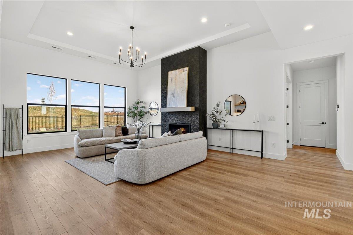 7714 West Flathead Lake Street, Unit ASPEN Eagle, ID 83616 - Photo 6 of 30 Living area with a fireplace, recessed lighting, light wood-style floors, a chandelier, and a tray ceiling
