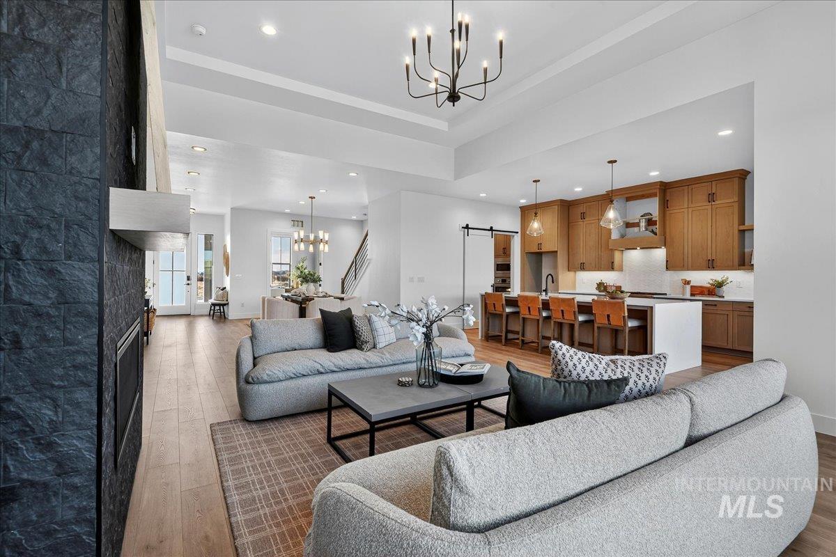 7714 West Flathead Lake Street, Unit ASPEN Eagle, ID 83616 - Photo 9 of 30 Living area with a chandelier, a barn door, light wood-type flooring, recessed lighting, and a raised ceiling