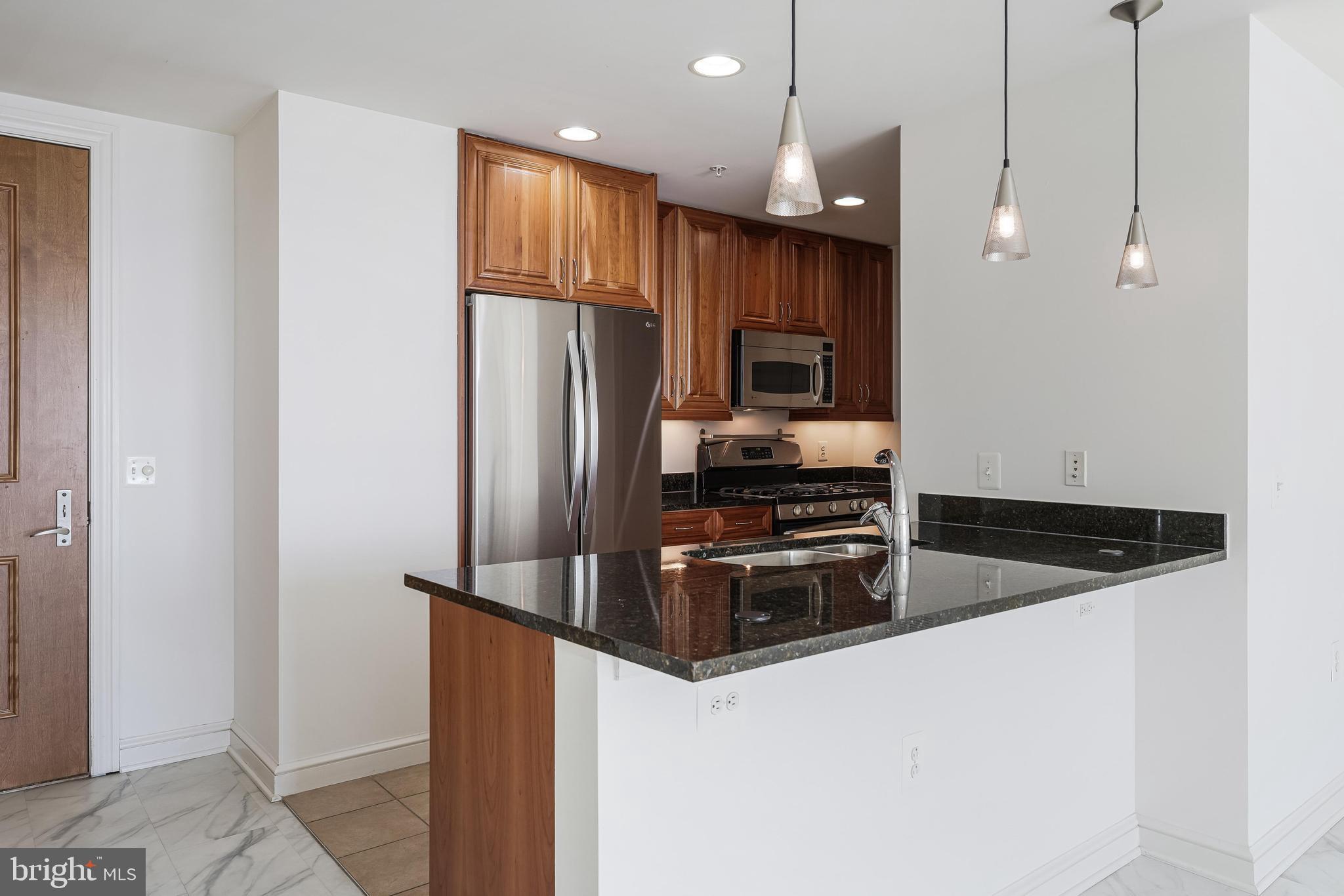 11990 Market Street, Unit 1414 Reston, VA 20190 - Photo 18 of 65 a kitchen with granite countertop a refrigerator and a sink