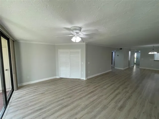an empty room with wooden floor and ceiling fan
