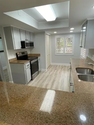 a kitchen with stainless steel appliances granite countertop a sink a stove top oven a counter space and cabinets