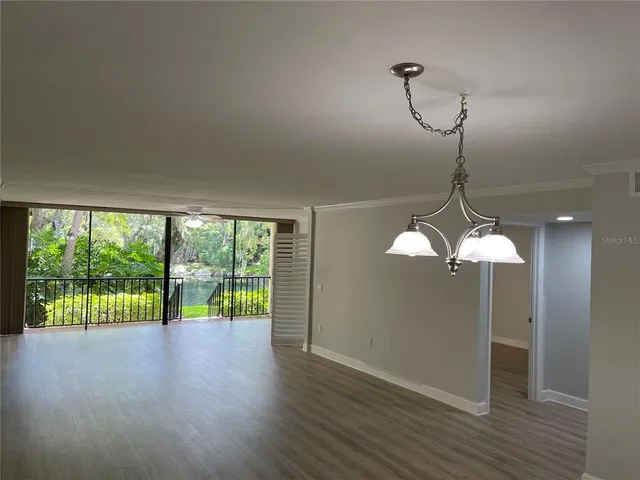 a view of a room with wooden floor chandelier and windows