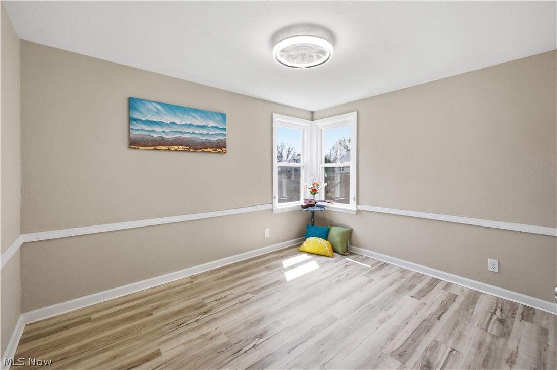 3232 Bears Den Road Youngstown, OH 44511 - Photo 17 of 38 Room featuring light wood-finish flooring, two large windows, a ceiling-mounted light fixture, and neutral painted walls with chair rail molding