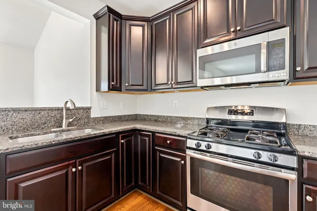 a kitchen with granite countertop a stove top oven cabinetry a sink and dishwasher