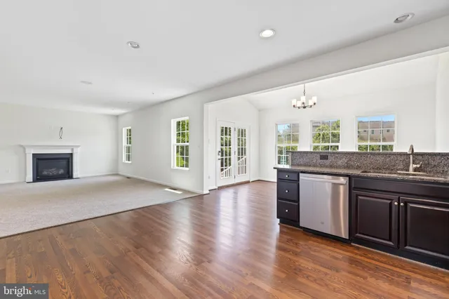 a open kitchen with granite countertop a stove top oven a sink dishwasher and a fireplace with wooden floor