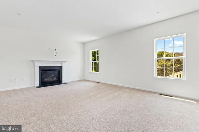 an empty room with a fireplace and windows