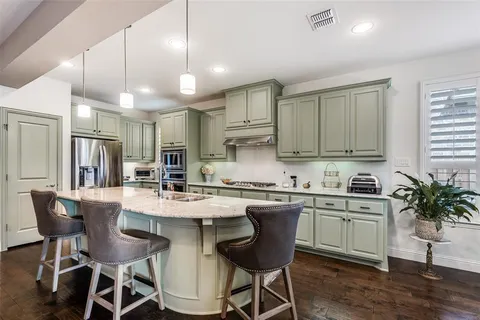 a kitchen with stainless steel appliances kitchen island granite countertop a dining table chairs and white cabinets