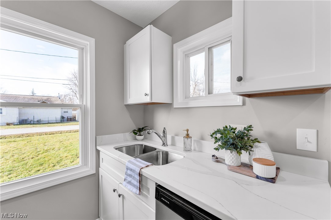 7501 Southland Road Mentor, OH 44060 - Photo 13 of 21 Kitchen with white cabinets, sink, light stone counters, and plenty of natural light