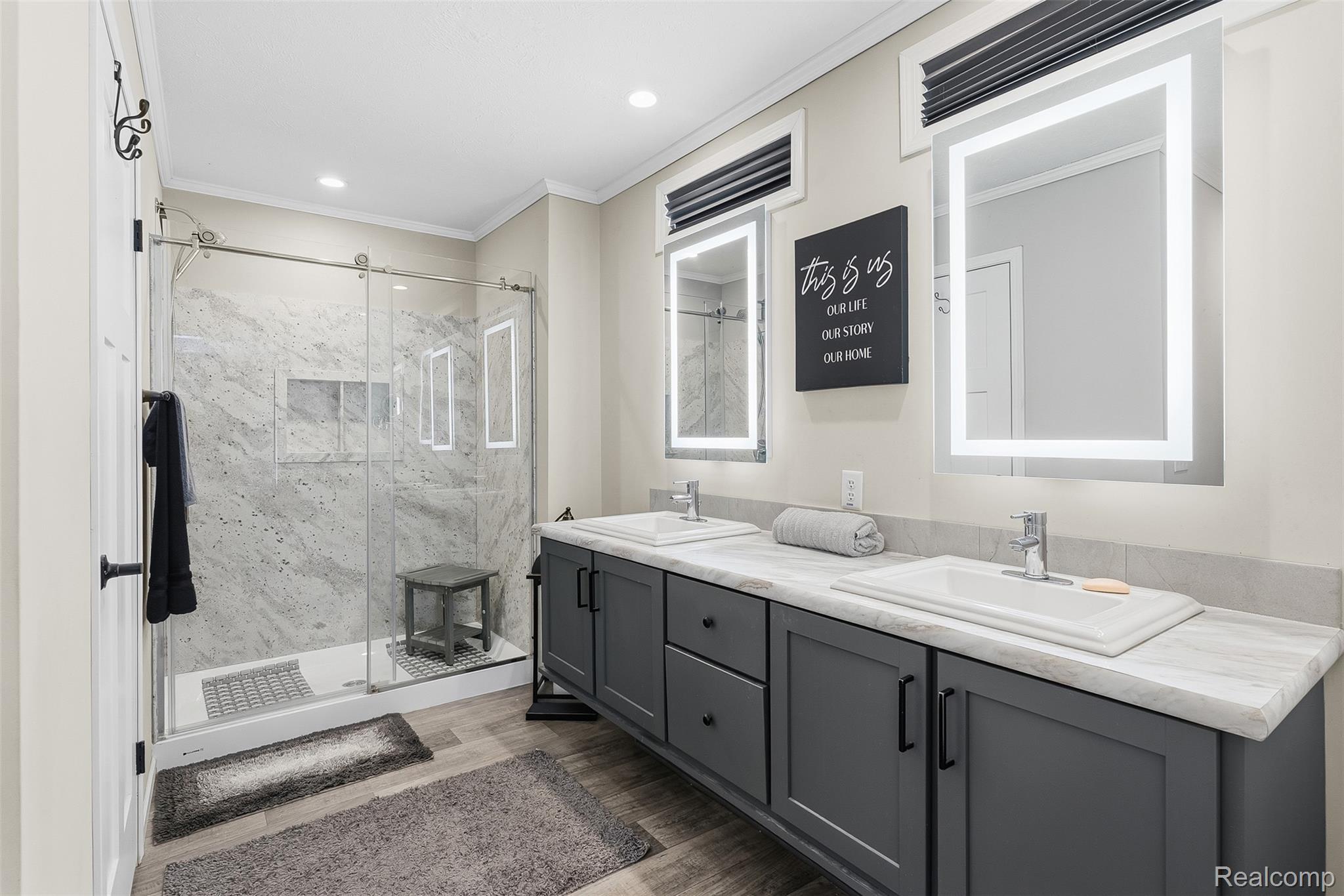 6450 Prince Boulevard Fenton, MI 48430 - Photo 12 of 31 Bathroom featuring a double vanity with dark cabinetry, light-toned countertops, and dual illuminated mirrors