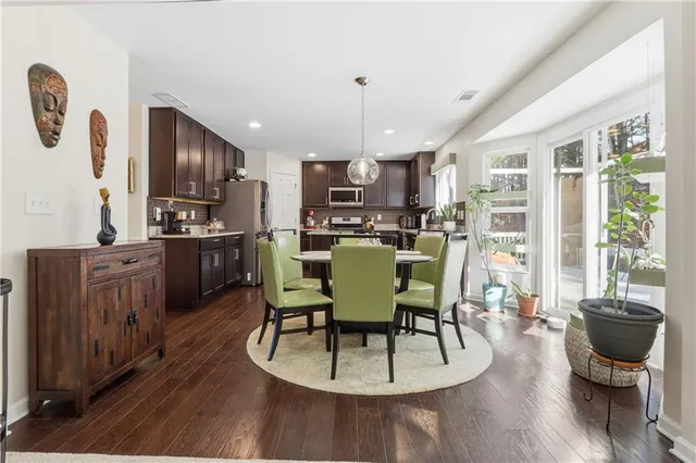 a kitchen with stainless steel appliances kitchen island granite countertop a stove a refrigerator a kitchen island a dining table and chairs with wooden floor