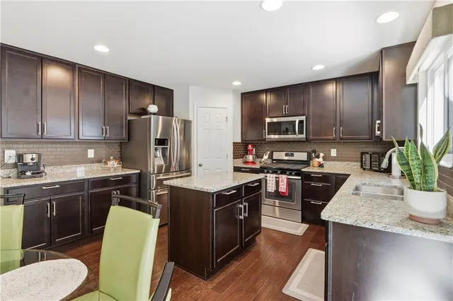 a kitchen with stainless steel appliances a sink stove refrigerator and cabinets