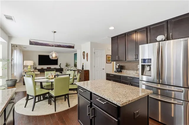 a kitchen with a refrigerator a stove a microwave oven a dining table and chairs