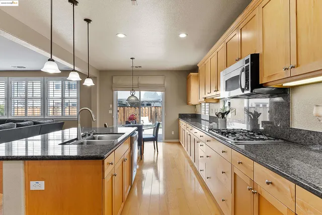 a kitchen with kitchen island granite countertop a sink a counter space appliances and cabinets