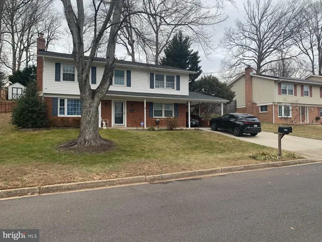 a front view of a house with a yard and large trees