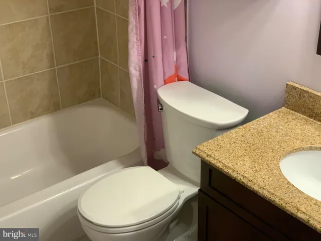 a bathroom with a granite countertop toilet sink and mirror