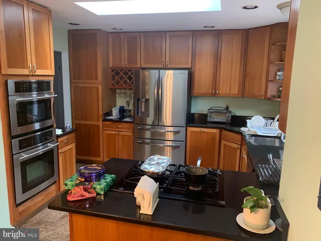 a kitchen with stainless steel appliances kitchen island granite countertop a refrigerator stove and microwave