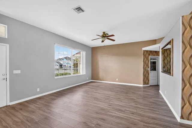 a view of an empty room with a window and wooden floor
