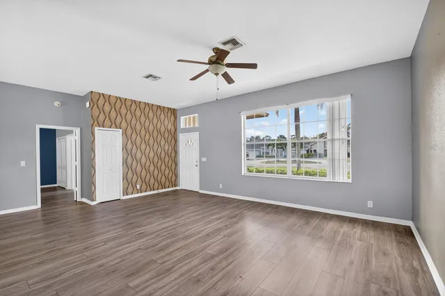 an empty room with wooden floor chandelier and windows