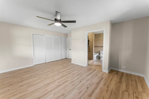an empty room with wooden floor a ceiling fan and windows