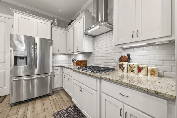 a kitchen with granite countertop stainless steel appliances a refrigerator a sink and cabinets
