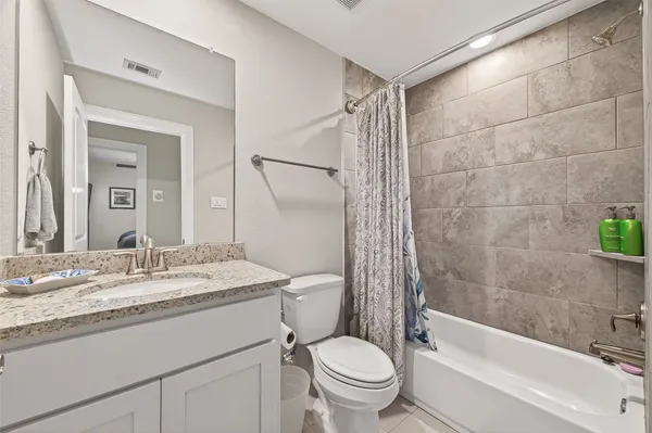 a bathroom with a granite countertop sink toilet mirror and bathtub