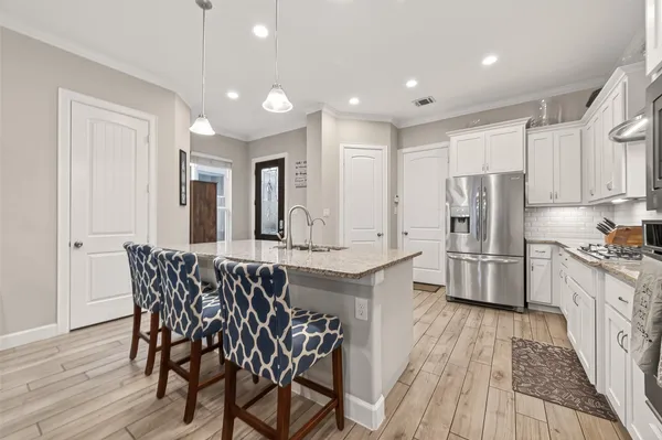 a kitchen with stainless steel appliances kitchen island granite countertop a kitchen island hardwood floor and a sink