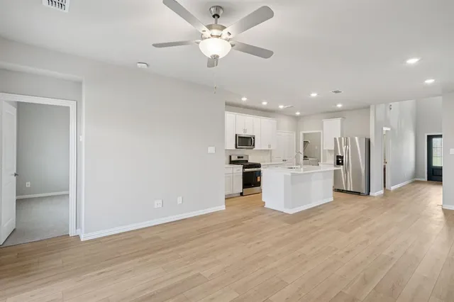 a view of kitchen with kitchen island wooden floor center island and stainless steel appliances