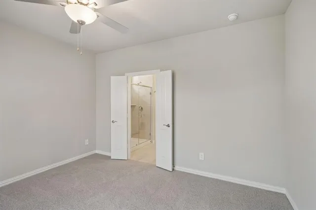 an empty room with a chandelier fan and closet area