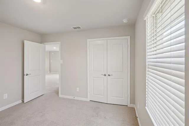 a view of an empty room with closet and a window