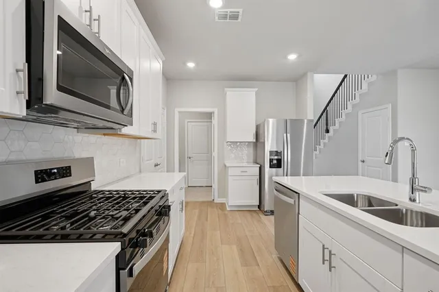 a kitchen with stainless steel appliances granite countertop a stove a sink and a microwave