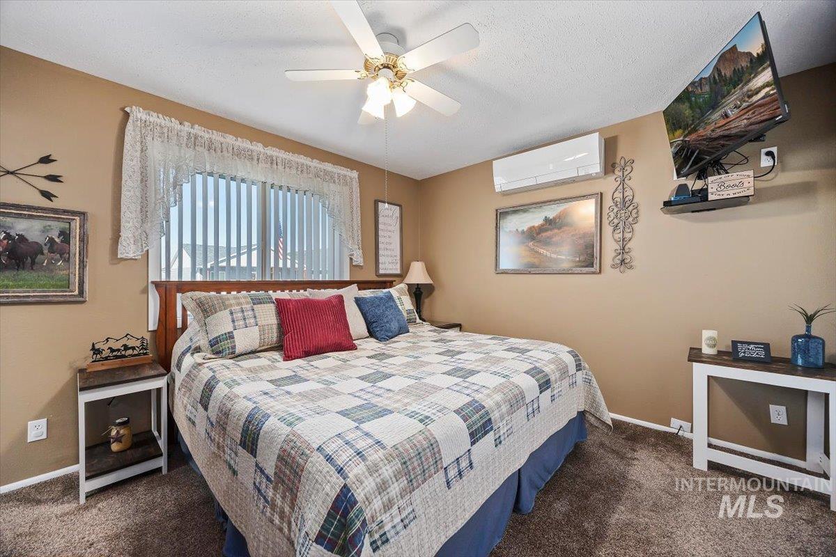 411 Mountain View Lane Burley, ID 83318 - Photo 22 of 38 Bedroom featuring dark colored carpet, a ceiling fan, a textured ceiling, and a wall mounted AC