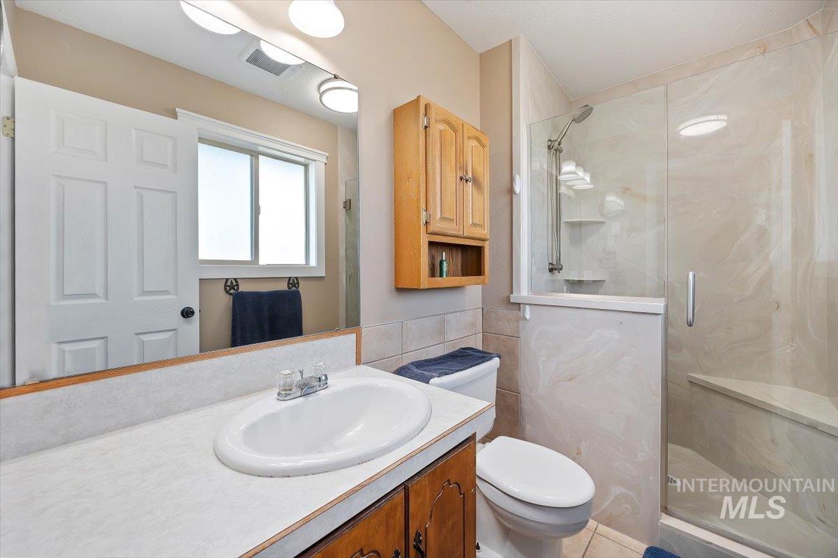 411 Mountain View Lane Burley, ID 83318 - Photo 24 of 38 Bathroom featuring vanity, a marble finish shower, and tile walls