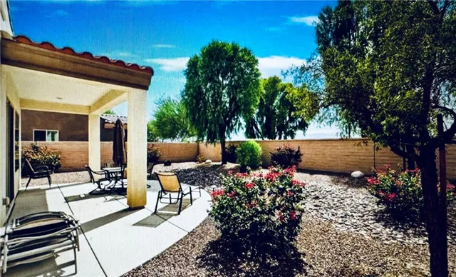 view of a patio with table and chairs potted plants and large tree