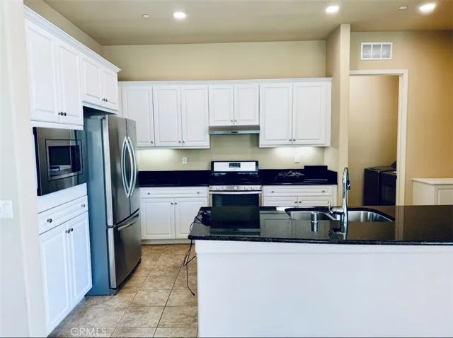 a kitchen with stainless steel appliances granite countertop a refrigerator and a stove