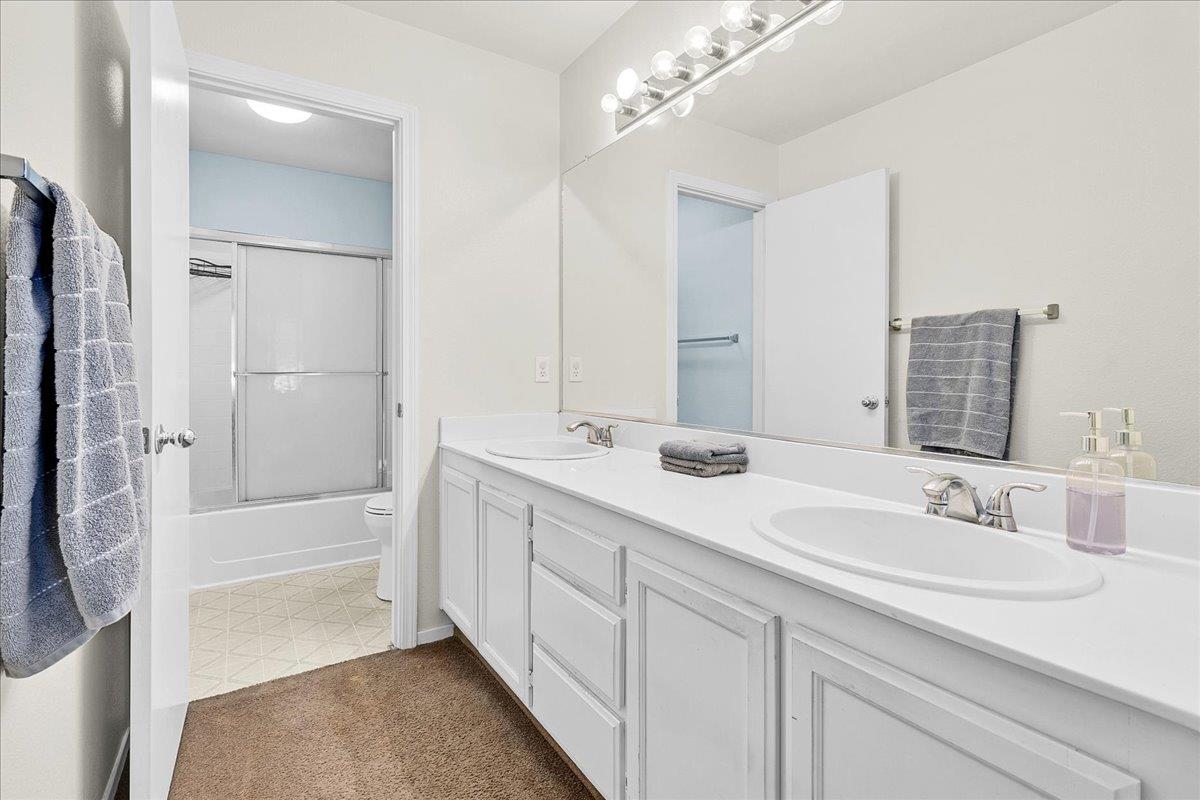 715 Skinner Street Soledad, CA 93960 - Photo 21 of 35 a bathroom with a double vanity sink a mirror and a bathtub
