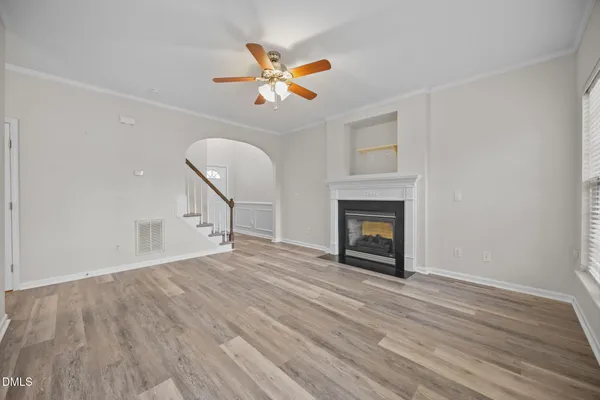 a view of an empty room with a window and wooden floor