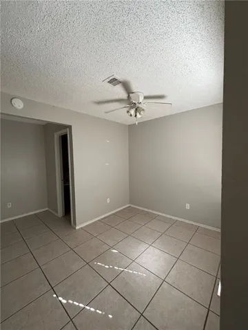a view of an empty room and chandelier fan