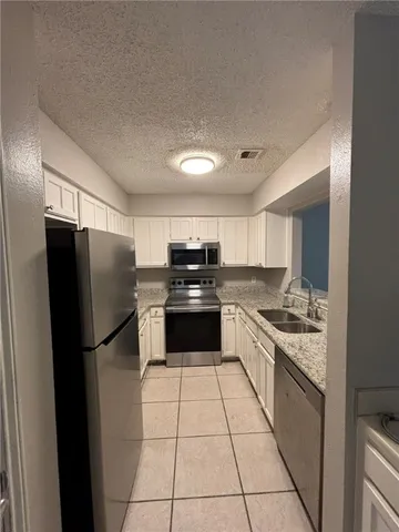 a kitchen with a refrigerator a stove top oven and cabinets