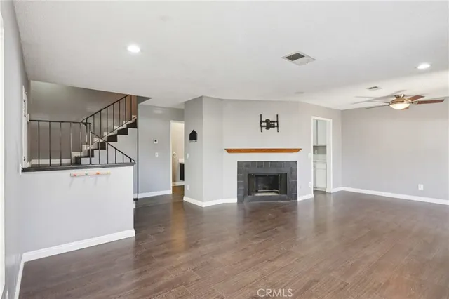 an empty room with wooden floor fireplace and windows