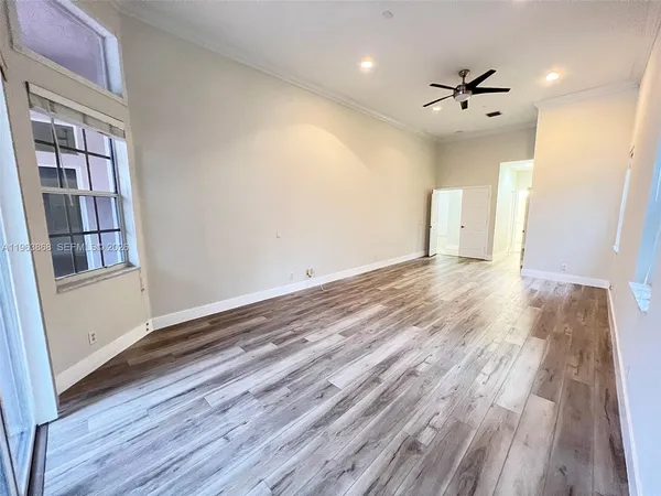 a view of an empty room with wooden floor and a window