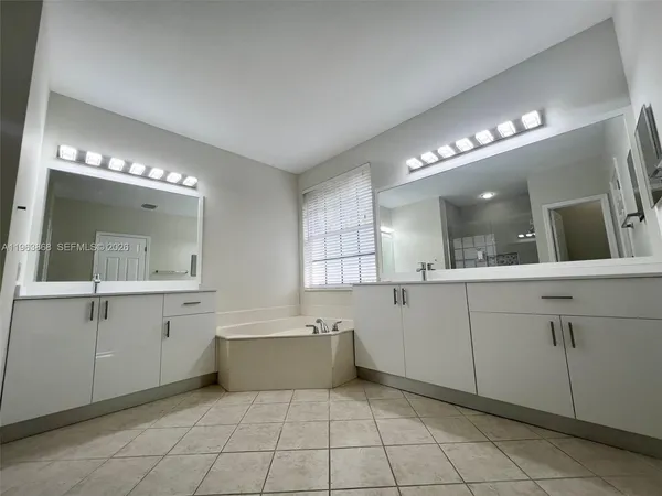 a large white bathroom with a large mirror vanity and a sink