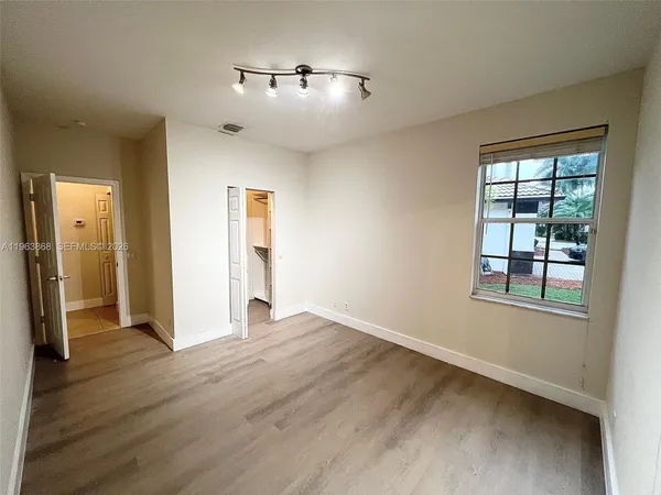 an empty room with wooden floor and windows