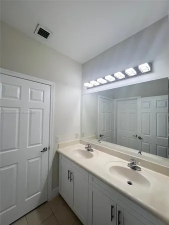 a bathroom with double vanity sink and a mirror