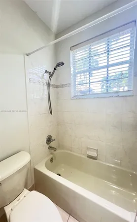 a bathroom with a toilet a bath tub and a window
