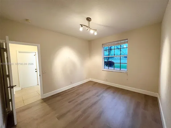 an empty room with wooden floor cabinet and windows