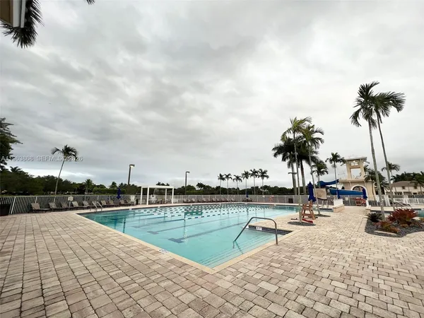 a view of swimming pool with table and chairs a barbeque with potted plants