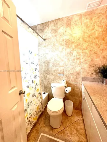 a bathroom with a granite countertop toilet and a sink