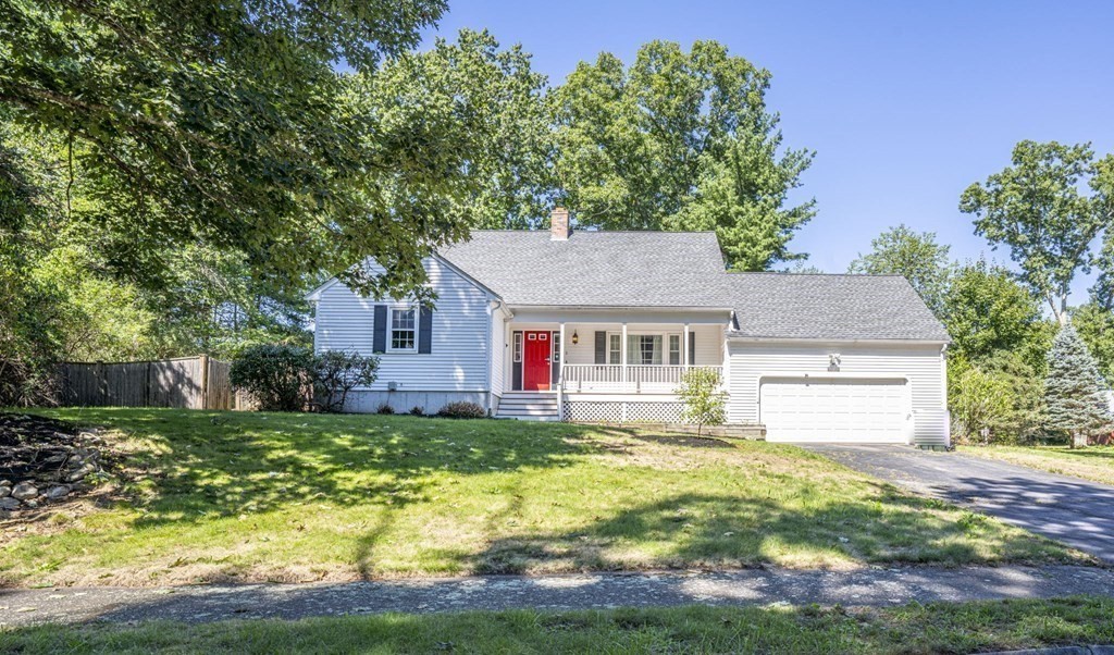 a house that is sitting in the grass with large trees and plants